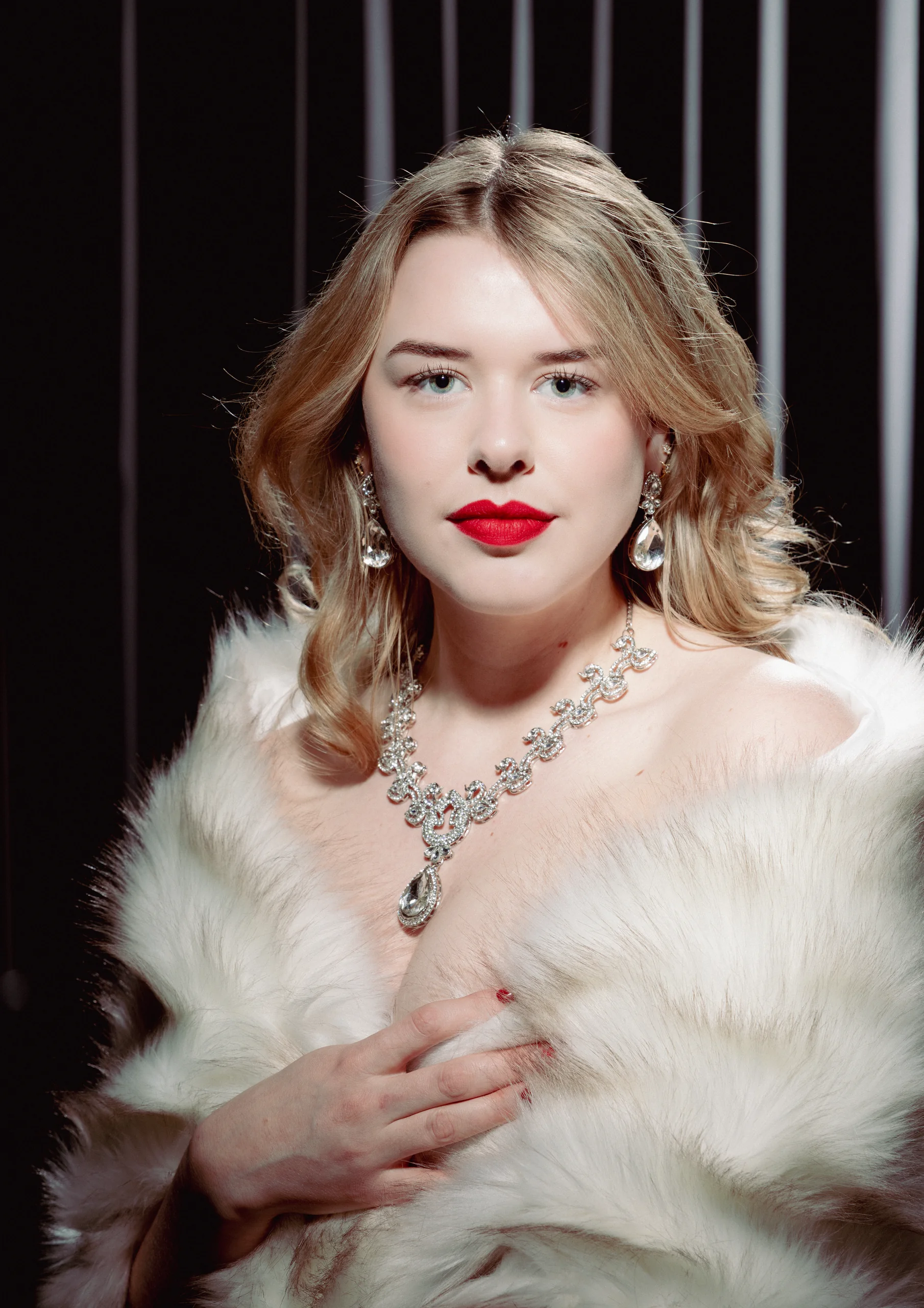 Glamourportret in kleur van een vrouw met rode lippen, parels en een witte bontstola
