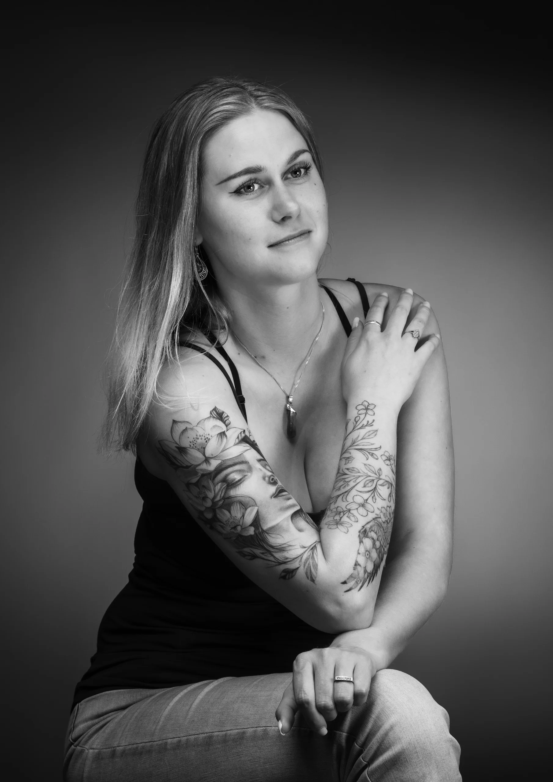 Zwart-witportret van een jonge vrouw met een getatoeëerde arm